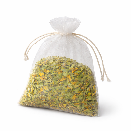 Clear drawstring bag filled with green and yellow dried herbs on a white background